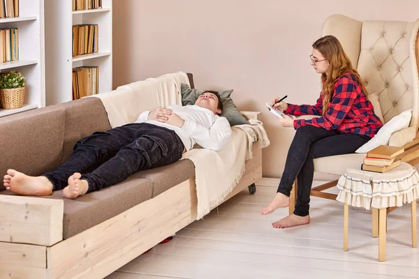 Psychothérapeute travaillant au bureau à domicile, homme allongé sur le canapé pendant un rendez-vous. — Photo