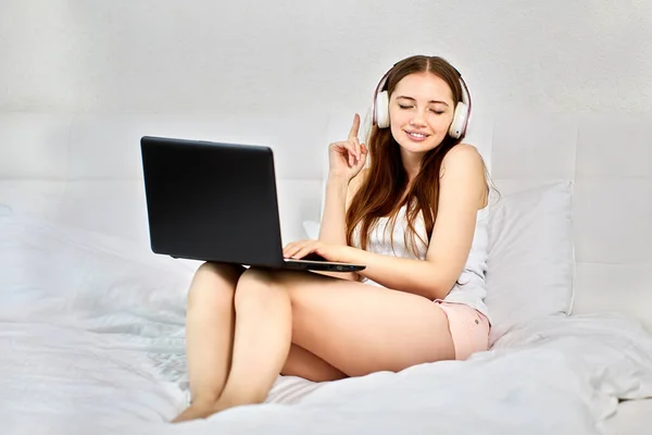 Frau mit Kopfhörer und Laptop im Bett, verdeckte die Augen. — Stockfoto