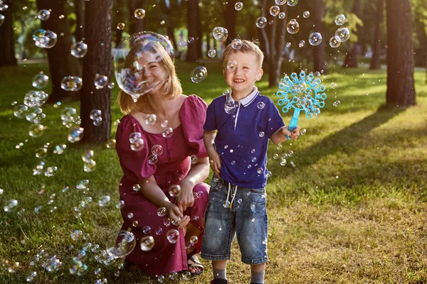 Woman with little boy play with bubbles outdoors. — Stock Photo, Image