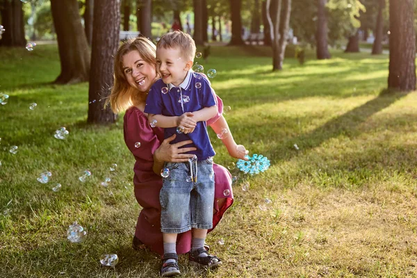 Bubbles as game for woman and her little son outdoors. — Stock Photo, Image