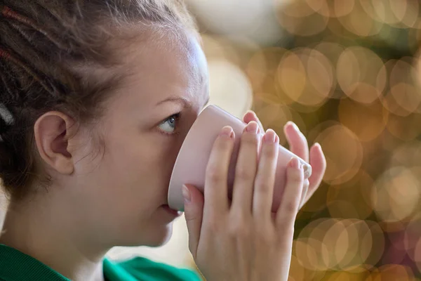 On christmas eve young woman with dreadlocks drinks coffee inside. — 图库照片