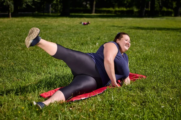 Duża kobieta build trenuje w parku w letni dzień. — Zdjęcie stockowe