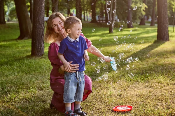 Soap bubble as game for woman and child outdoors. — Stock Photo, Image