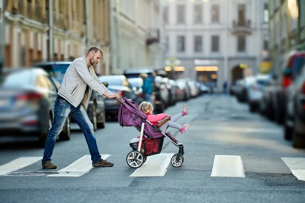 Father with little daughter in baby carriage outdoors. Stockbild