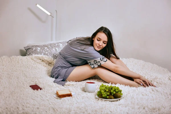 Sabahlık giymiş bir kadın kahvaltısına bakıyor..