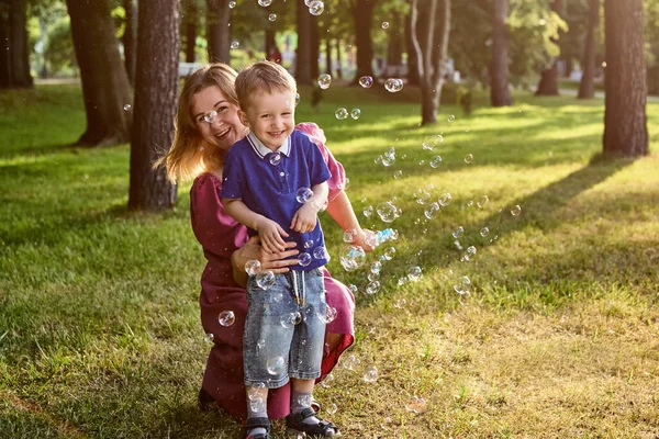Child with mother blows soap bubble outside. — Stock Photo, Image