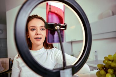 Makyaj, akıllı telefon ve halka ışığı kullanan bir kadından canlı yayın.