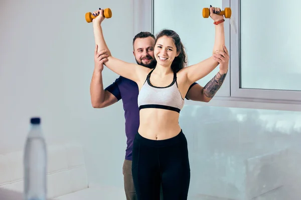 Fitness à la maison par femme avec mari-entraîneur à l'aide d'haltères. — Photo