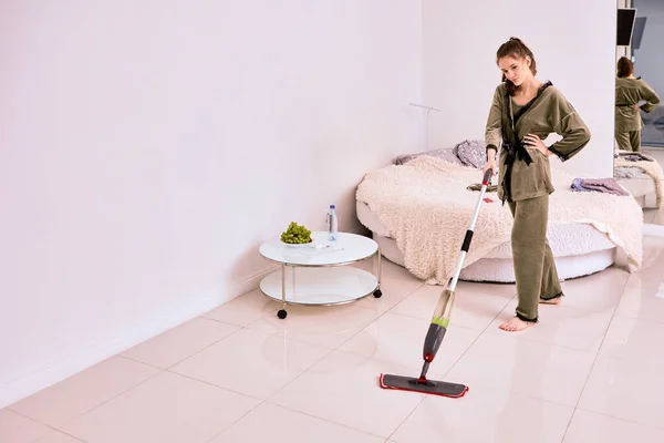 Женщина чистит пол с помощью плоской швабры с помощью спрея. — стоковое фото