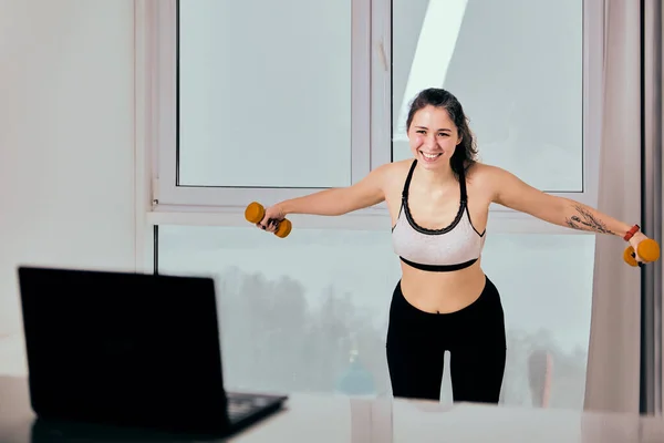 Clases de streaming en vivo de fitness en el portátil para la mujer sonriente en ropa deportiva. — Foto de Stock