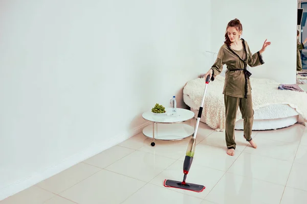 Frau säubert Fliesenboden mit Hilfe von Wischmopp mit Spray. — Stockfoto