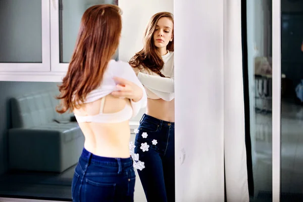 Kvinnan klär av sig framför spegeln inuti. — Stockfoto