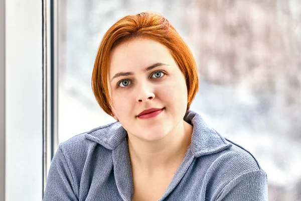 Peinado bob con el pelo teñido de rojo por la joven mujer europea en el interior. — Foto de Stock