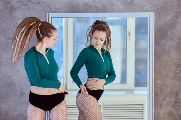 Dancer beoordeelt slankheid van haar heupen voor spiegel. — Stockfoto