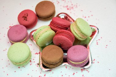 Çeşitli Fransız badem kurabiyeleri. Bir tabakta yıldız şeklinde küçük Fransız hamur işleri. Fıstıklı, çikolatalı, ahududulu ve çilekli makarna..