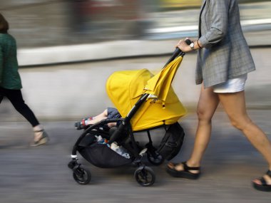 İnsanlar hareket halinde, bebek arabalı bir kadın.