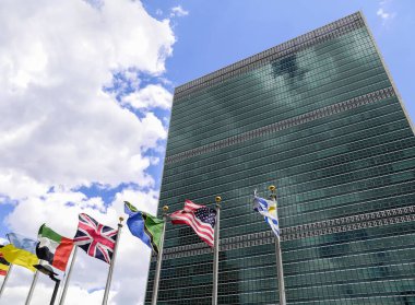Birleşmiş Milletler binasının arka planına karşı farklı ülkelerin bayrakları