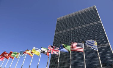Birleşmiş Milletler binasının arka planına karşı farklı ülkelerin bayrakları