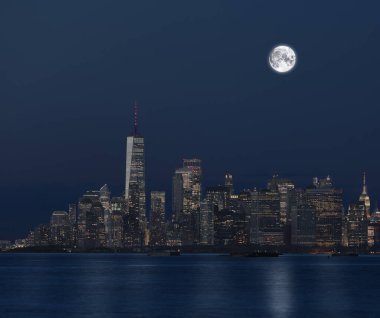 View of Manhattan at night from the river and the full moon