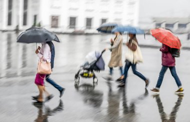 Defocused image of people with umbrellas in the rain