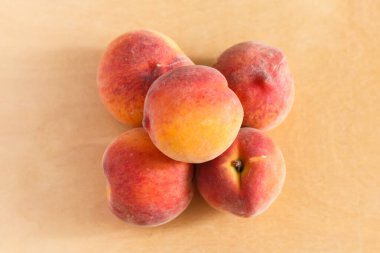 Kahverengi bir masanın üstünde beş şeftali piramidi.