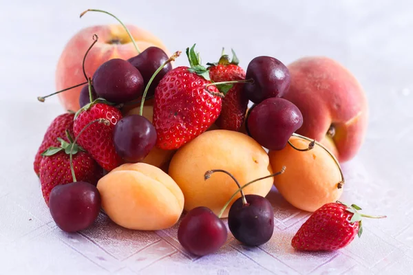 白色桌布上的几个桃子 樱桃和草莓 — 图库照片#