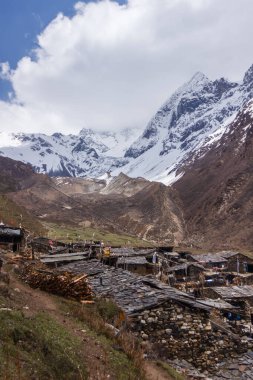 Manaslu bölgesindeki köyün taş evleri karla kaplı dağlara karşı.