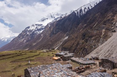 Manaslu bölgesindeki köyün taş evleri karla kaplı dağlara karşı.