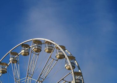 Parlak mavi gökyüzüne karşı kapalı teleferikli beyaz dönme dolaba yaklaş.