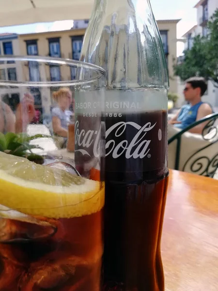 シウテデラ メノルカ スペイン 10月2018 アイスキューブとレモンのスライスを含むガラスとカフェテーブルの上にスペイン語でテキストとコカコーラのボトルのクローズアップ — ストック写真