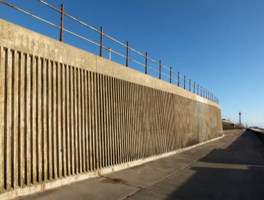 Kuzey Blackpool 'daki yaya geçidi boyunca beton deniz yatağı ve korkuluklar var. Öğleden sonra güneş ışığı altında kule ve kasabayla birlikte.