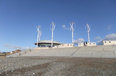 Blackpool, Lancashire, Birleşik Krallık 'taki Cleveland' daki sahil şeridi boyunca yürüyen insanlar - 4 Mart 2022 - Kafe ve modern rüzgar türbinleriyle Blackpool