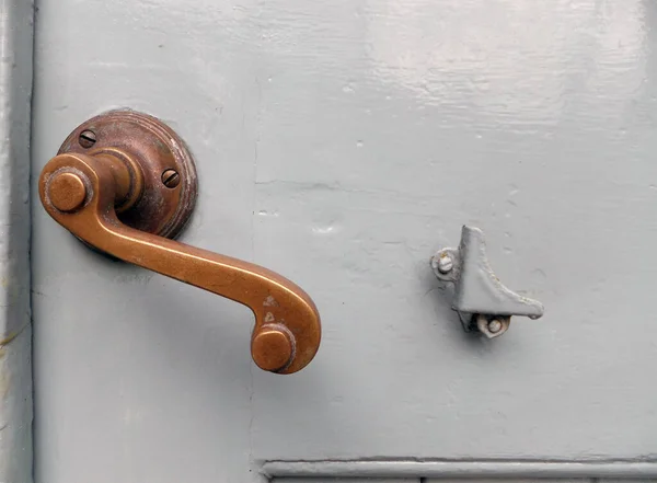 old curved bronze door handle on an exterior grey painted house door