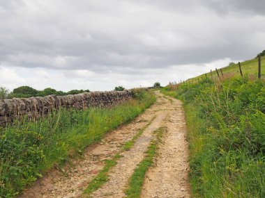 Narrow dirt lane running alongside a dry stone wall surrounded hillside meadows in calderdale west yorkshire near hebden bridge