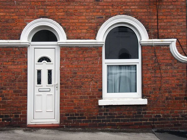 白い装飾画と典型的な古いレンガ造りの英国のテラスハウスの白いフロントドアと窓 — ストック写真