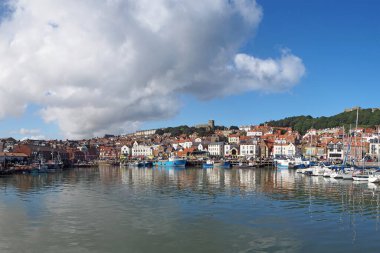 Scarborough, Kuzey Yorkshire, Birleşik Krallık - 10 Eylül 2022: Scarborough limanının uzun panoramik manzarası bir yaz günü su ve kasaba binalarına yansıyan balıkçı tekneleriyle