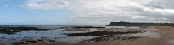 long panoramic view of the beach at Scarborough south bay on a cloudy summer day with the castle and hotels in the distance
