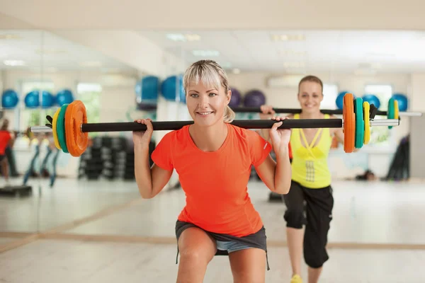 Two girls with a barbell — Stock Photo, Image