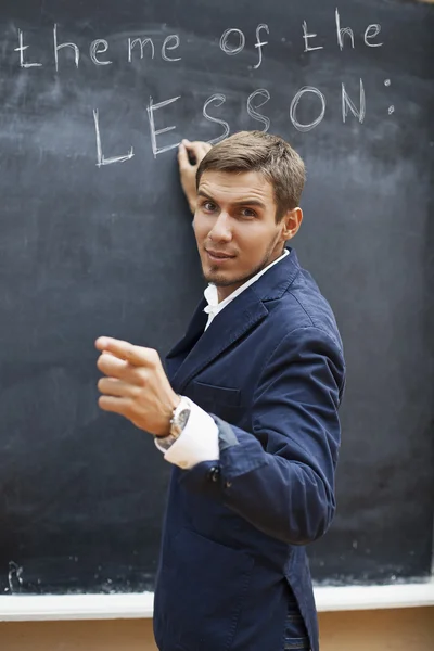 Junge Lehrerin schreibt mit Kreide an Tafel — Stockfoto