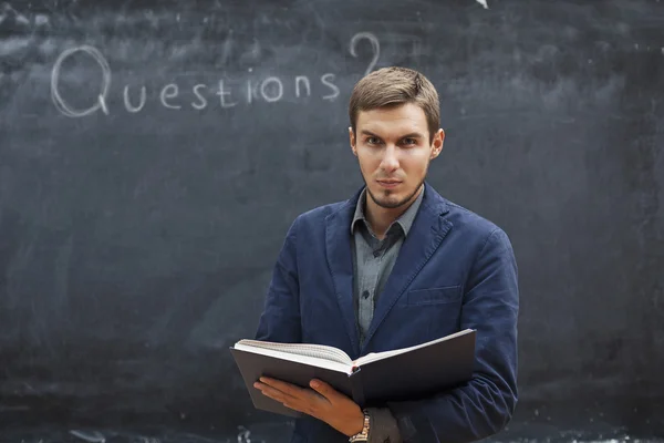 Teacher with textbook costs around the board with the inscriptio — Stock Photo, Image