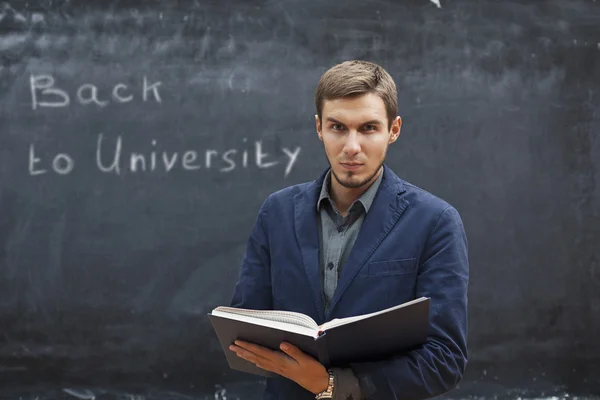 Teacher with textbook costs around the board with the inscriptio — Stock Photo, Image