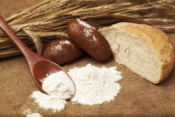 Flour on a wooden spoon and bakery products — Stock Photo, Image