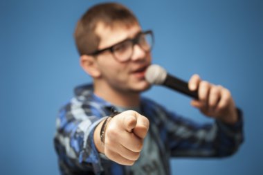 mavi arka plan üzerinde mikrofon kullanarak şarkı