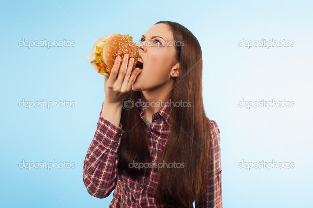 Girl eats a hamburger. Portrait in the studio.