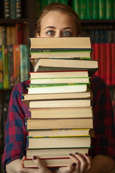 Flickan i bibliotek med en massa böcker — Stockfoto