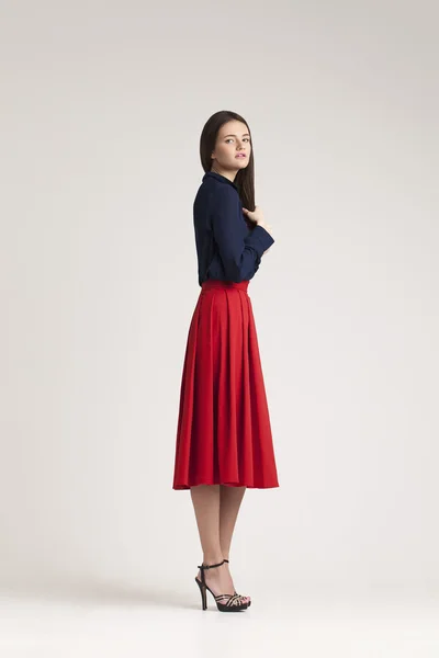 Ung dam i klänning poserar på grå bakgrund. röd — Stockfoto