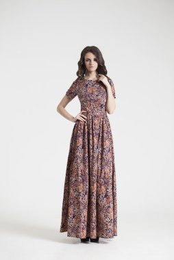 gri arka plan üzerinde poz elbiseli genç esmer Bayan