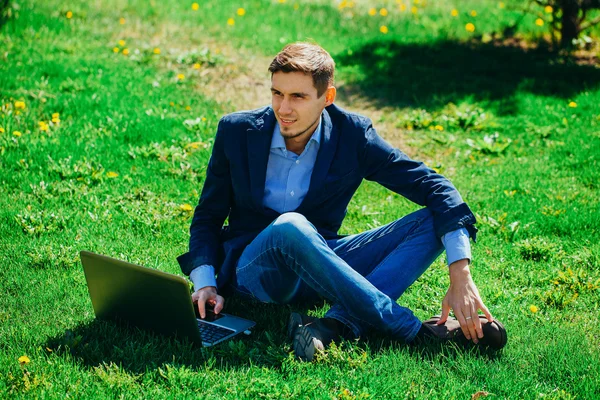 Ein junger Mann mit Laptop draußen. Park — Stockfoto