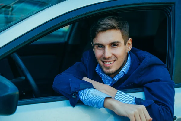 Un hombre de negocios guapo sonriente sentado en el coche. Sonríe —  Fotos de Stock