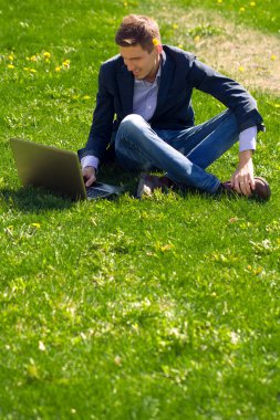 çimenlerin üzerinde genç iş adamı. Skype konuşurken. Açık. 